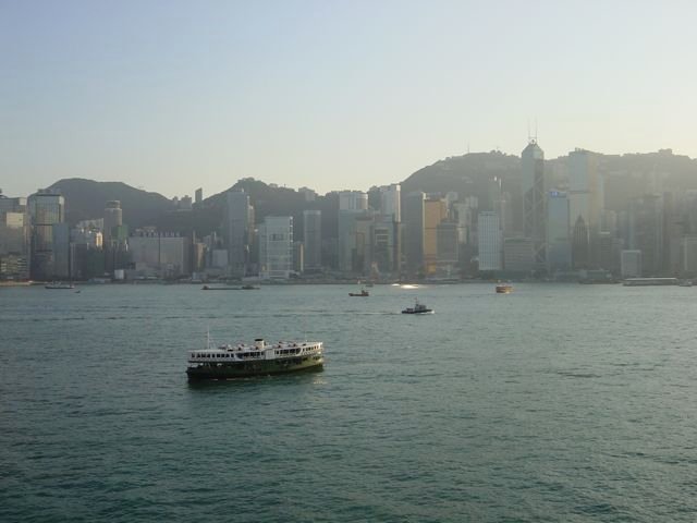 Victoria Harbour with a Star Ferry crossing and Hong Kong Island skyline backed by mountains