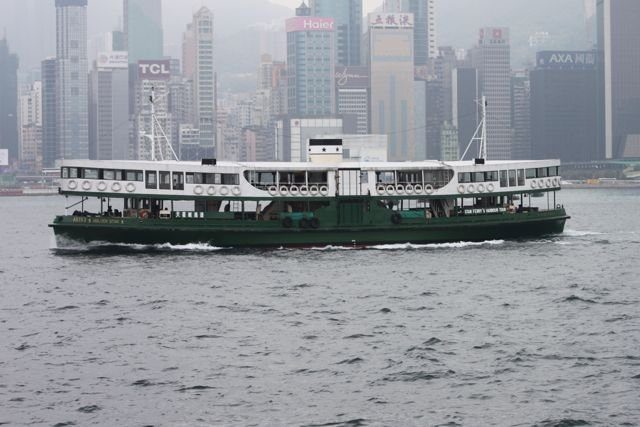 Star Ferry crossing Victoria Harbour with Hong Kong Island skyline on a hazy day