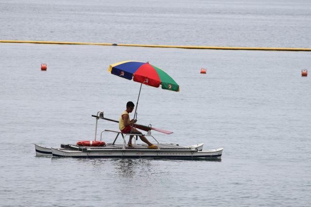 Lifeguard on a floating platform under a colourful umbrella