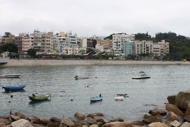 Small boats in a harbour bay with low-rise village buildings along the waterfront