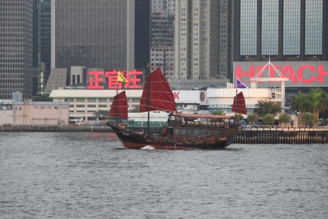 Traditional Chinese junk boat with red sails crossing Victoria Harbour