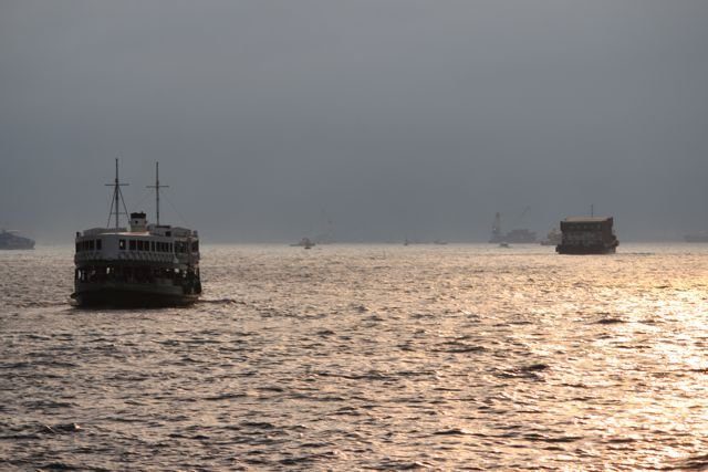 Star Ferry crossing the harbour at dusk with golden light on the water