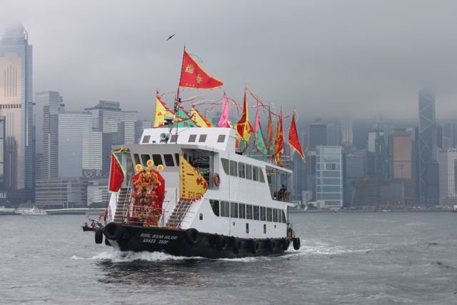 Decorated festival boat with flags crossing Victoria Harbour
