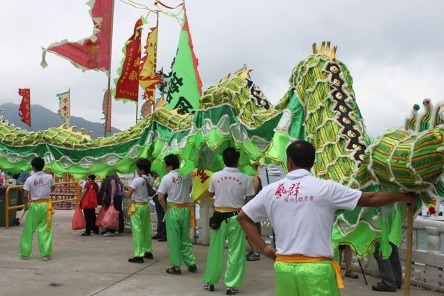 Dragon dance team preparing a green dragon at a waterfront festival