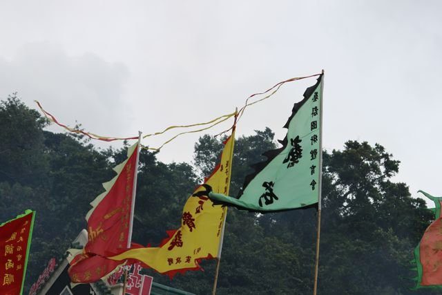 Colourful festival flags with Chinese text flying against green hills