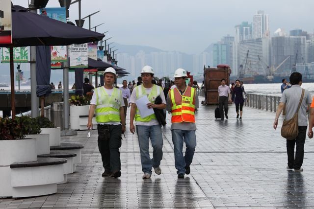 Construction workers in hi-vis vests walking along the TST promenade