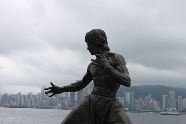 Bruce Lee statue on the Tsim Sha Tsui waterfront with skyline behind