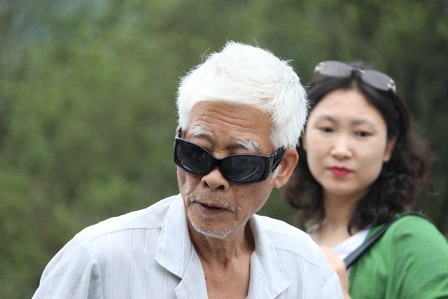 Elderly man with white hair and sunglasses in a park
