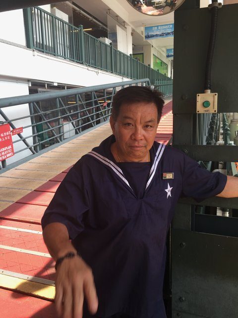 Star Ferry crew member in uniform standing at the gangway on the pier