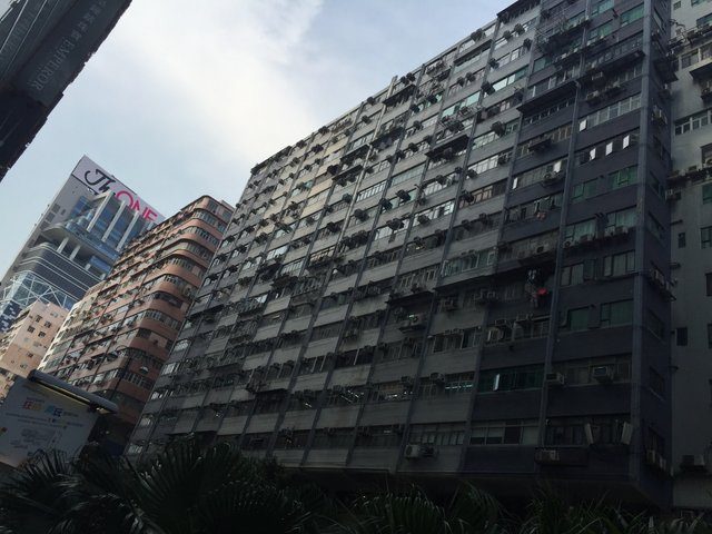 Densely packed residential tower block viewed from below, air units covering every floor