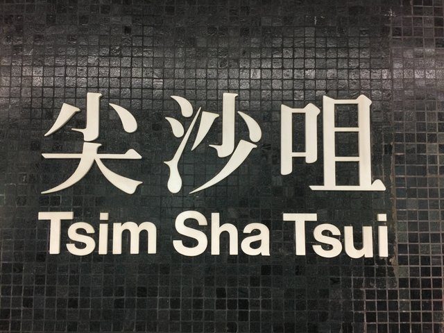 Tsim Sha Tsui MTR station name sign in Chinese and English on dark mosaic tiles