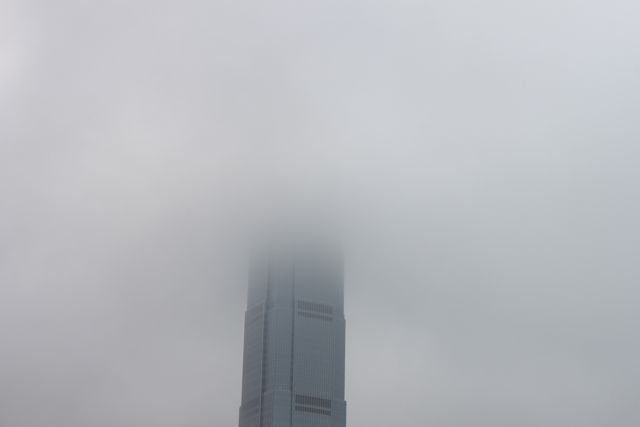 Skyscraper top disappearing into low cloud and fog