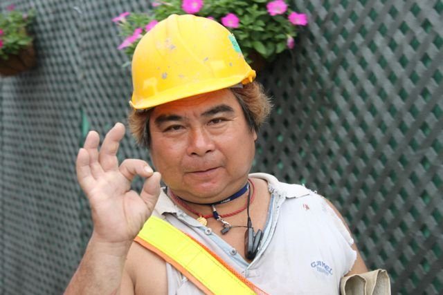 Construction worker in a yellow hard hat giving an OK hand sign