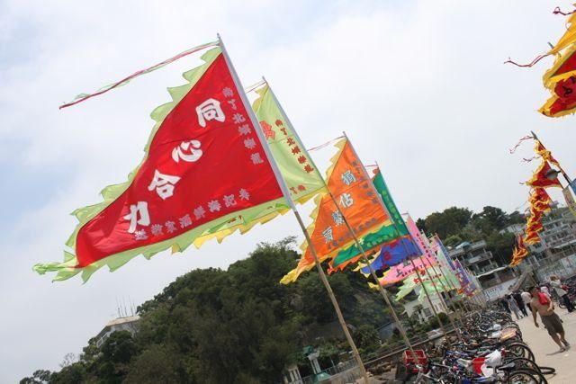 Colourful festival flags with Chinese text flying at a beachside celebration