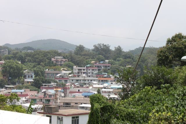 Low-rise village houses with green hills and mountains behind on an outlying island
