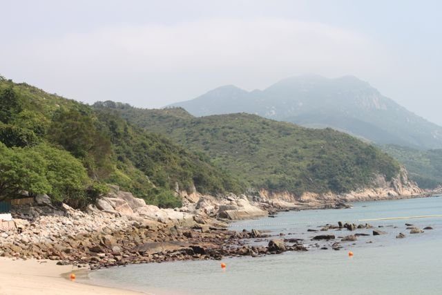 Rocky coastline and beach on a Hong Kong outlying island with green hills