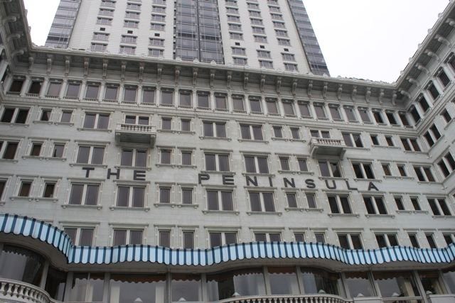 The Peninsula Hotel facade with striped awnings looking up at the tower