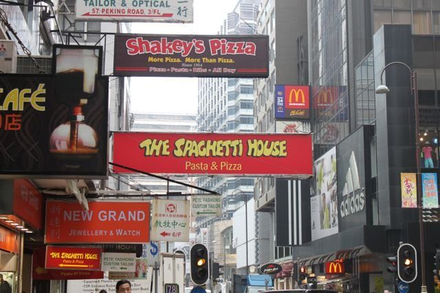Neon signs for restaurants and shops crowding a Tsim Sha Tsui street