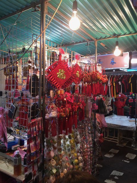 Dimly lit market stall hung with red Chinese lucky knots and decorations