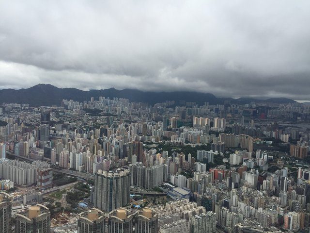 Storm clouds over a vast carpet of Kowloon residential towers stretching to the mountains