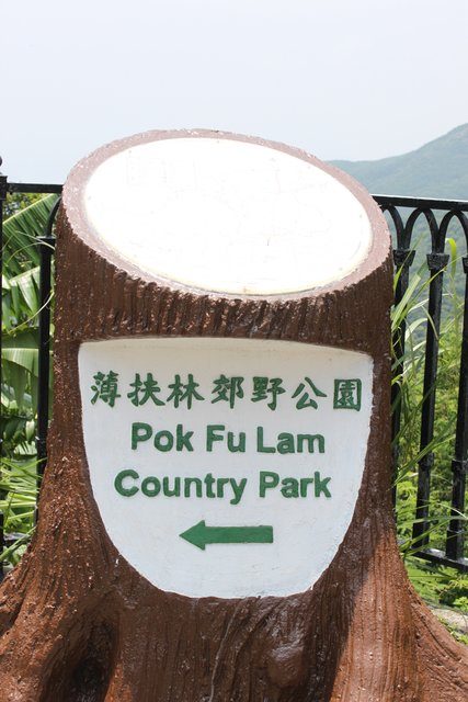 Tree-stump sign for Pok Fu Lam Country Park with bilingual directional arrow