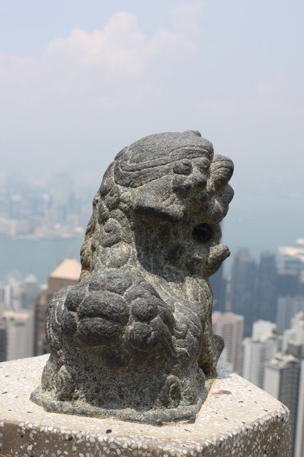 Stone foo dog sculpture on a parapet with the Hong Kong skyline behind