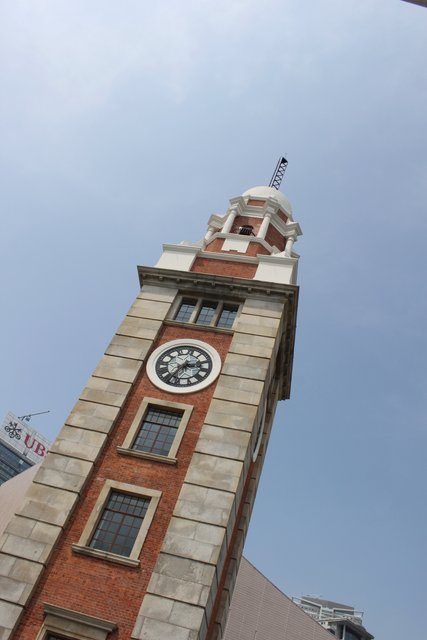 Tsim Sha Tsui Clock Tower seen from below, red brick and white stone against blue sky