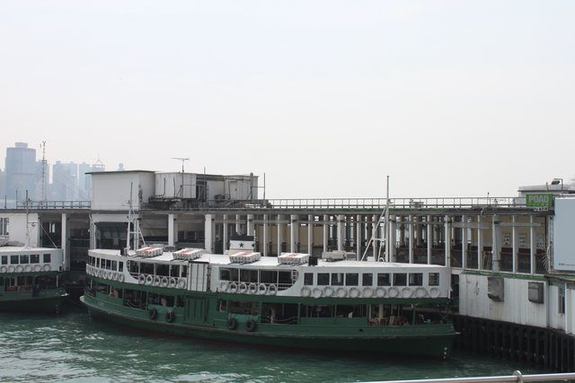 Star Ferry berthed at its pier, Hong Kong Island skyline faint in the haze beyond