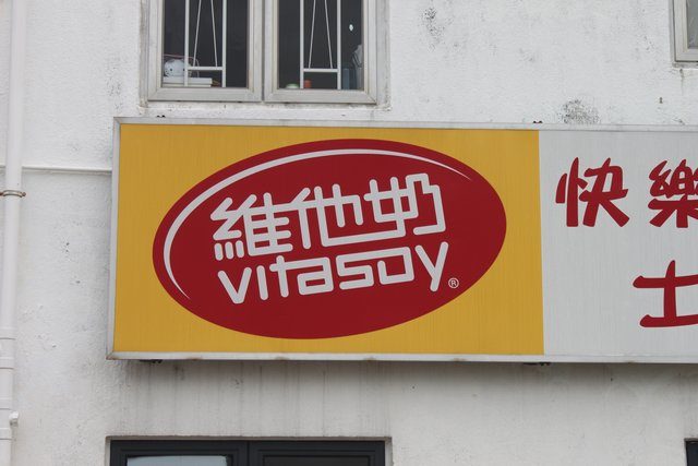 Vitasoy logo sign in Chinese and English on a white rendered wall