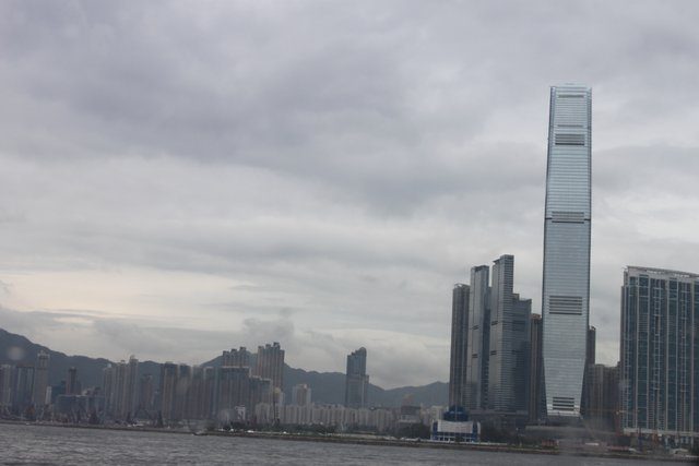 ICC tower dominating the West Kowloon waterfront under a heavy overcast sky